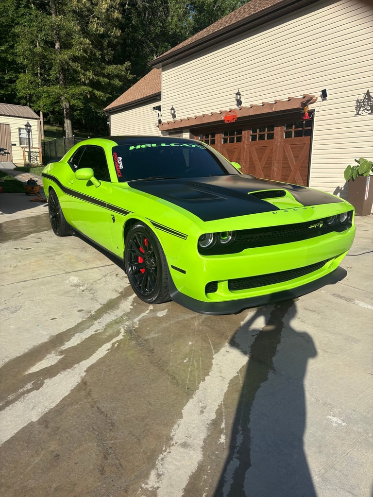 Neon lime green Dodge Challenger muscle car parked in driveway with garage in background